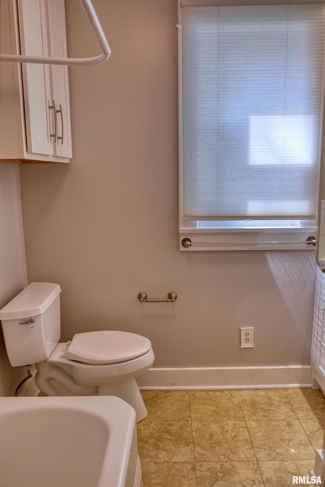 full bathroom with toilet, tile patterned floors, baseboards, and a bathtub