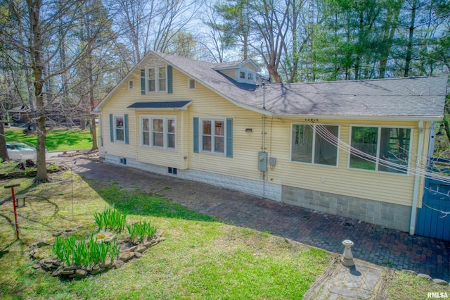 view of side of property with roof with shingles and a lawn