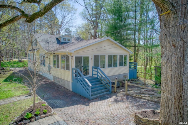 bungalow-style home featuring fence and a sunroom