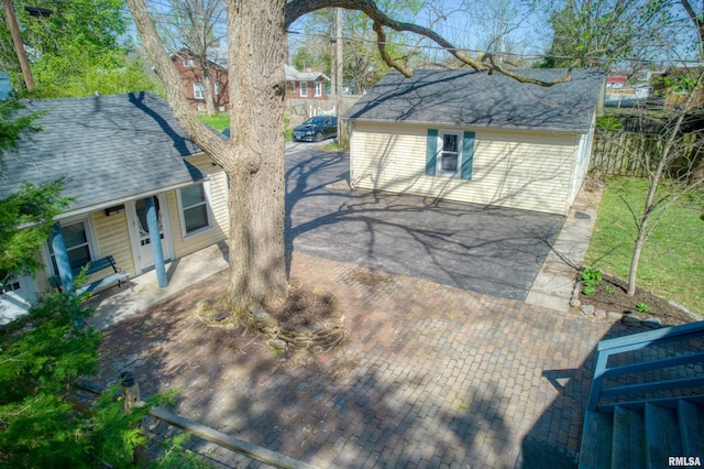 view of side of property featuring roof with shingles and fence