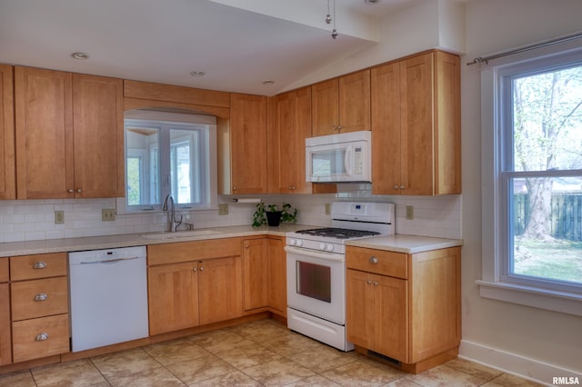 kitchen with white appliances, light countertops, a sink, and decorative backsplash