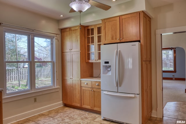 kitchen featuring plenty of natural light, baseboards, and white fridge with ice dispenser