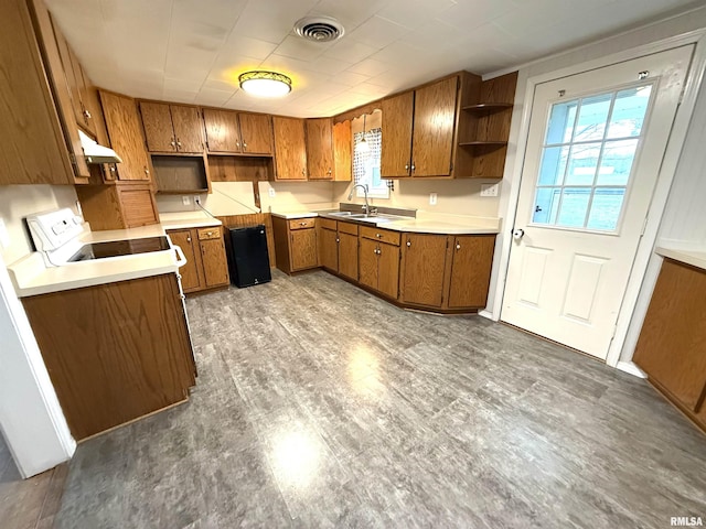 kitchen featuring visible vents, open shelves, a sink, under cabinet range hood, and brown cabinets