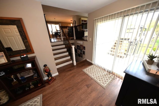 entryway featuring a chandelier, stairs, dark wood-type flooring, and baseboards