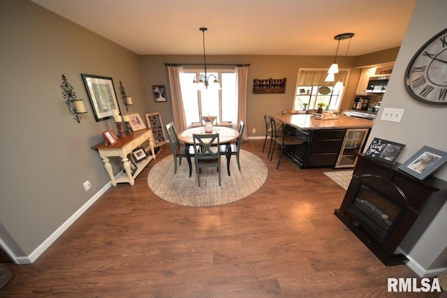 dining space with dark wood-style flooring, baseboards, and a notable chandelier