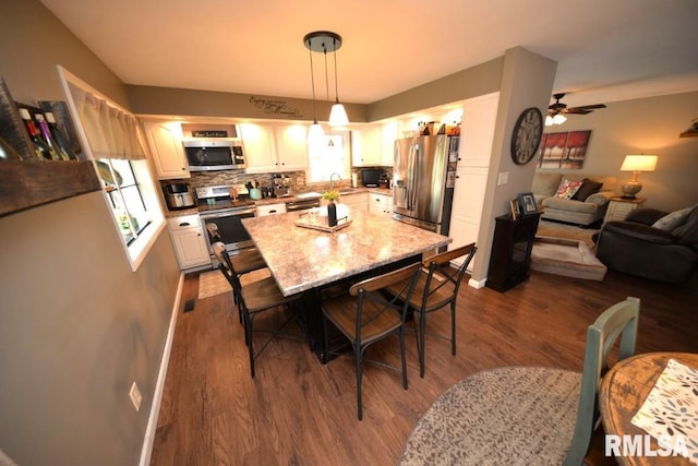 dining room featuring dark wood-type flooring, baseboards, and a ceiling fan