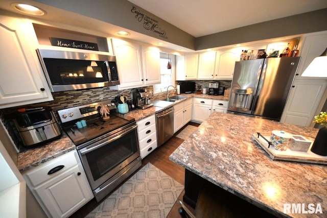 kitchen with tasteful backsplash, appliances with stainless steel finishes, dark wood-style floors, white cabinetry, and light stone counters