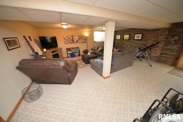 interior space with baseboards, a drop ceiling, and brick wall