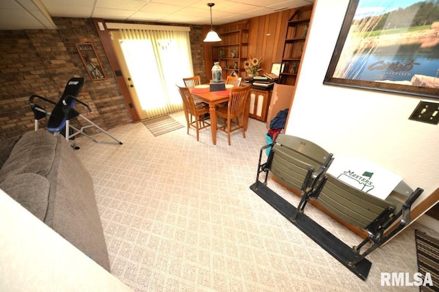 dining room featuring a paneled ceiling and brick wall