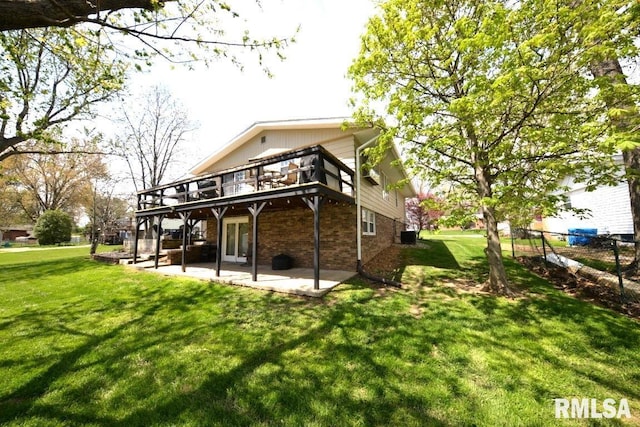 back of house featuring a yard, a patio area, a deck, and brick siding