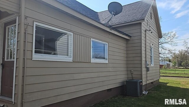 318 W Raymond St, Harrisburg, IL 62946 - view of property exterior featuring roof with shingles, central air condition unit, a lawn, and crawl space