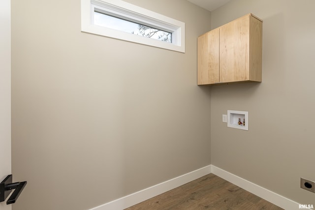 washroom featuring electric dryer hookup, baseboards, washer hookup, cabinet space, and wood finished floors