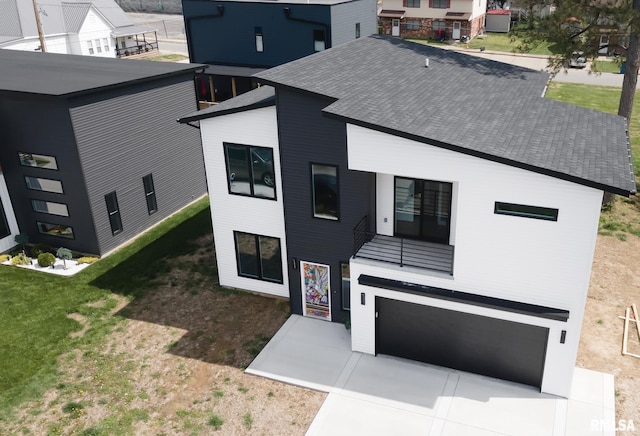 view of front facade featuring a front yard, an attached garage, a shingled roof, and driveway