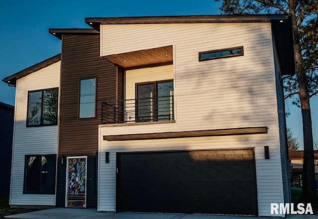 view of front of property featuring a garage, driveway, and a balcony