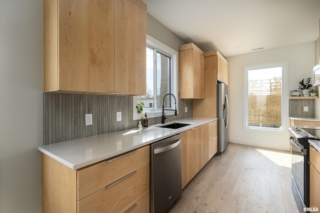 kitchen with light wood-style floors, modern cabinets, appliances with stainless steel finishes, a sink, and light brown cabinetry
