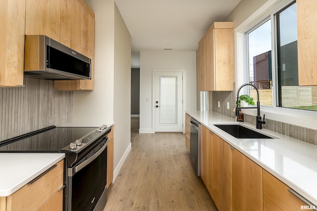 kitchen featuring appliances with stainless steel finishes, a sink, modern cabinets, and baseboards
