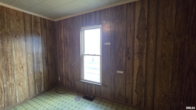 205 Shaw St, Harrisburg, IL 62946 - spare room featuring crown molding, visible vents, wood walls, and plenty of natural light