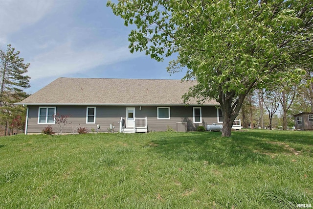 rear view of property with a shingled roof and a lawn