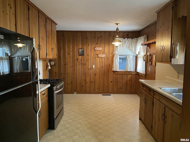 kitchen with visible vents, a sink, light countertops, freestanding refrigerator, and stainless steel gas range oven