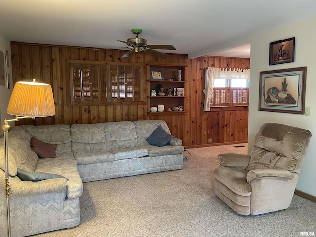 living room with wooden walls, ceiling fan, and carpet