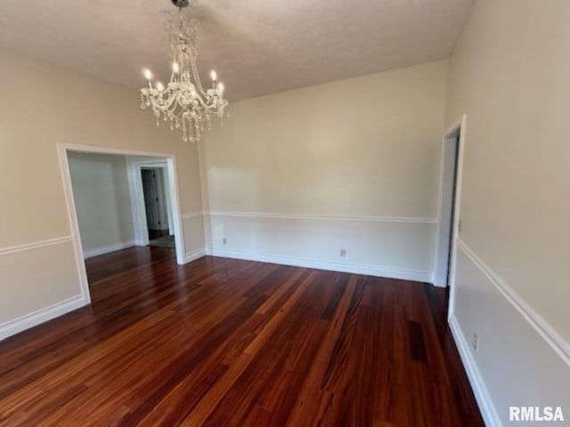 unfurnished dining area featuring an inviting chandelier and dark wood-style floors