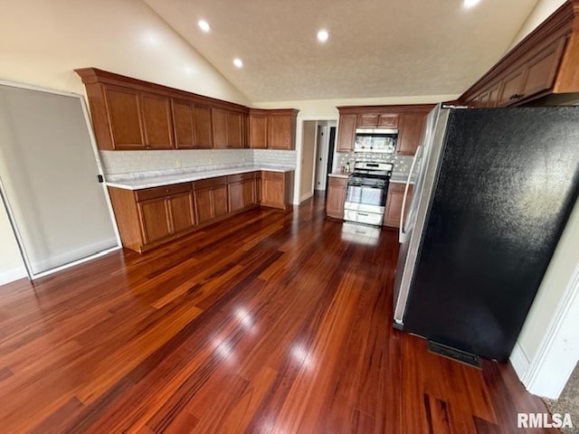 kitchen with vaulted ceiling, recessed lighting, appliances with stainless steel finishes, light countertops, and backsplash