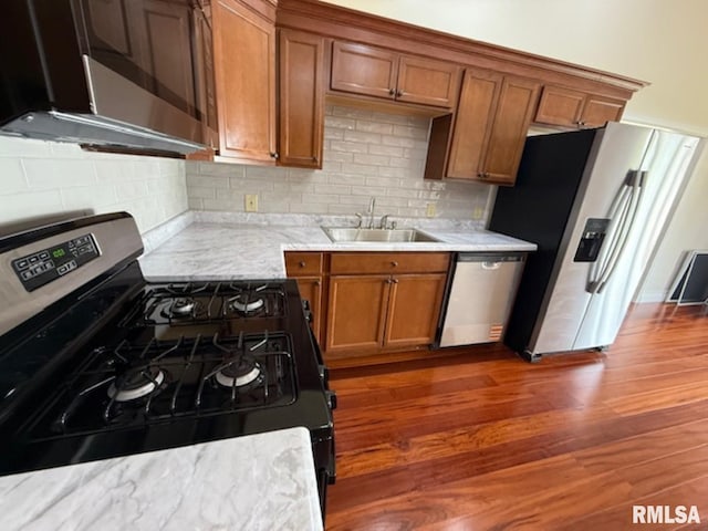 kitchen with brown cabinets, a sink, backsplash, and appliances with stainless steel finishes
