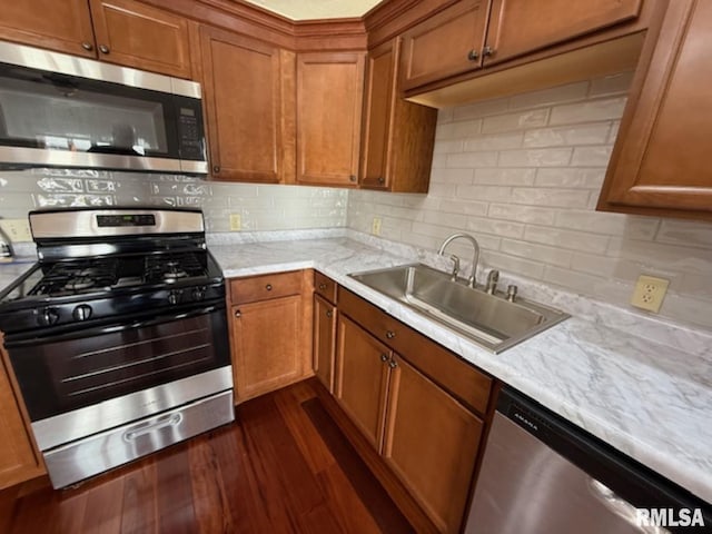 kitchen with a sink, tasteful backsplash, appliances with stainless steel finishes, and brown cabinets