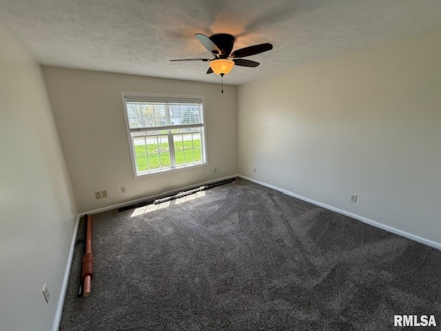 spare room featuring baseboards, a ceiling fan, dark colored carpet, and a textured ceiling