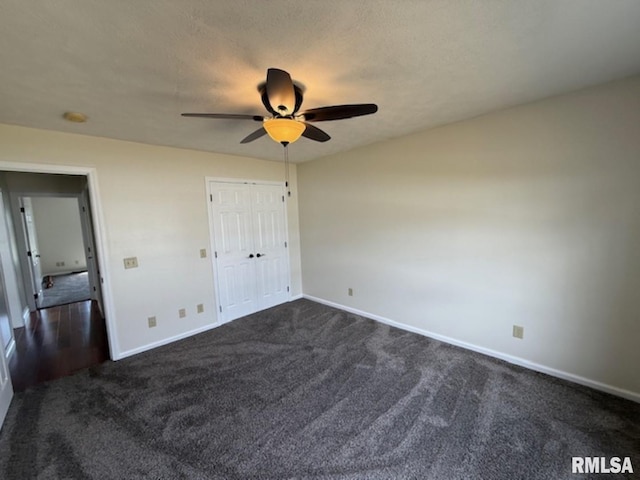 unfurnished bedroom featuring dark carpet, baseboards, a ceiling fan, and a closet