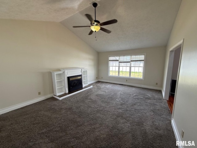 unfurnished living room with dark carpet, a textured ceiling, a ceiling fan, a fireplace with raised hearth, and lofted ceiling