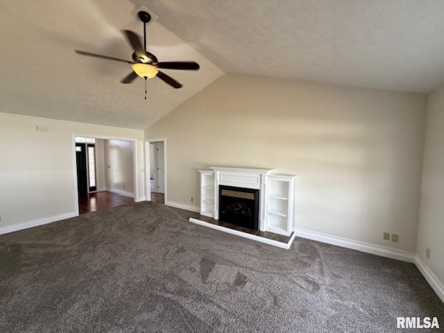 unfurnished living room featuring dark colored carpet, baseboards, a fireplace with raised hearth, lofted ceiling, and ceiling fan