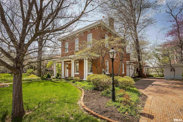 italianate house featuring brick siding, a front yard, and a chimney