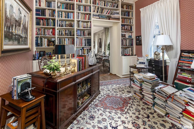 office space featuring built in shelves, wood finished floors, and wallpapered walls
