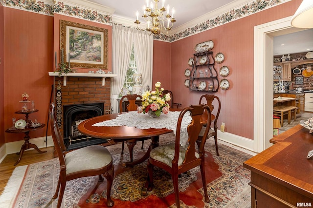 dining area featuring baseboards, an inviting chandelier, a brick fireplace, crown molding, and wood finished floors