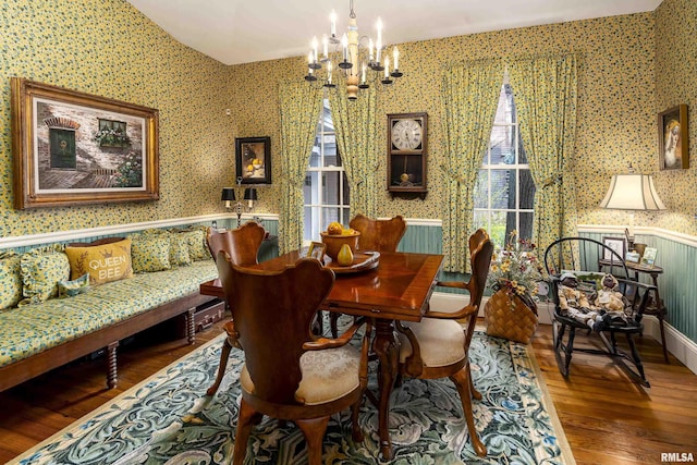 dining area with a chandelier, wallpapered walls, and wood finished floors
