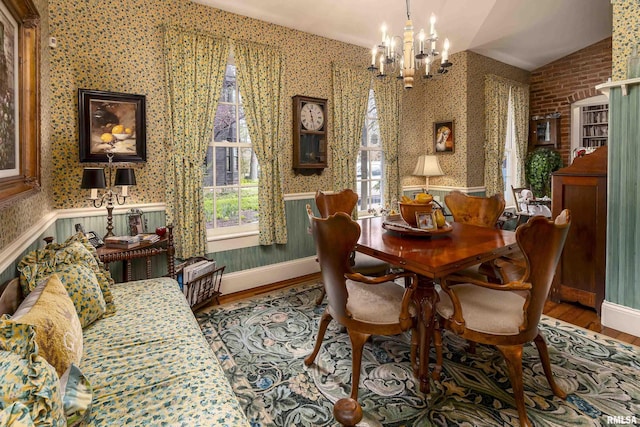 dining area featuring vaulted ceiling, a chandelier, wood finished floors, wallpapered walls, and baseboards