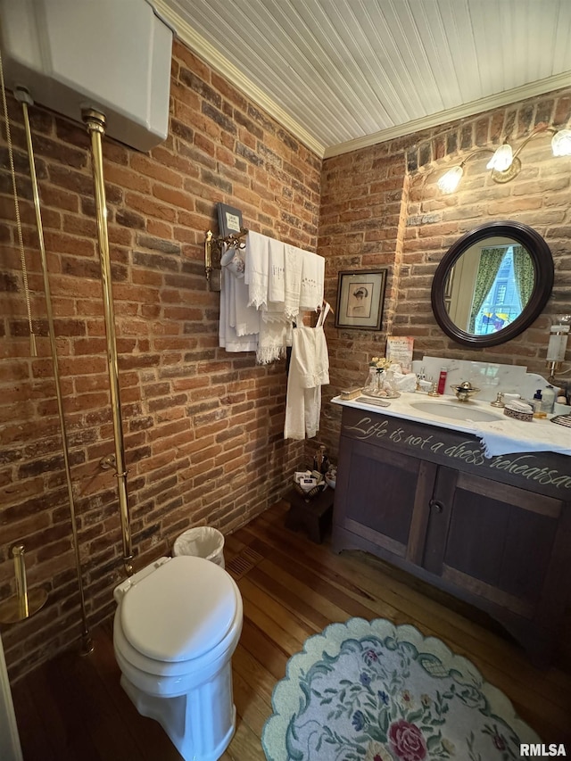 bathroom with brick wall, vanity, hardwood / wood-style flooring, and toilet