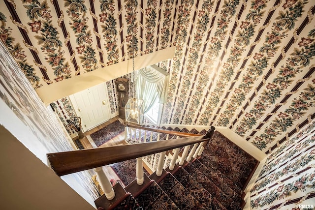 stairs with a notable chandelier and wallpapered walls