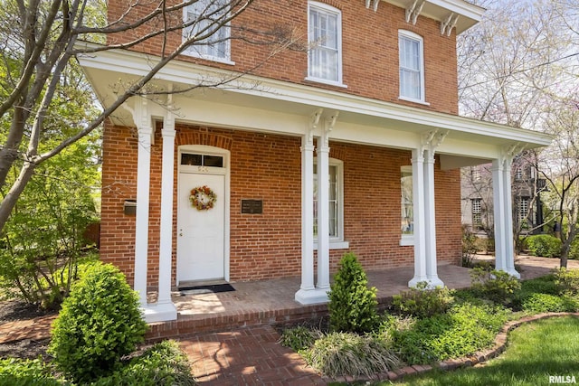 property entrance with a porch and brick siding