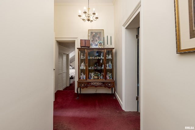 hallway featuring a chandelier, carpet, baseboards, and crown molding