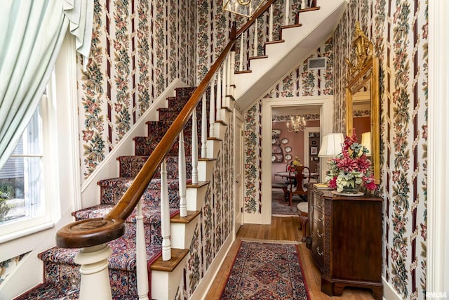 stairway with wallpapered walls and wood finished floors