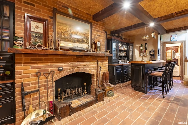 bar featuring beam ceiling, brick floor, and bar area