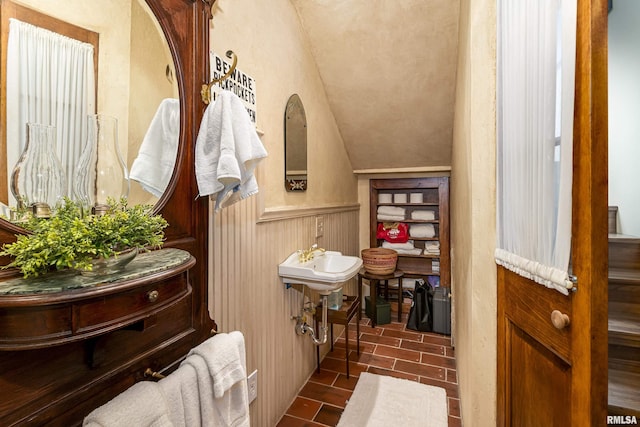 bathroom with wainscoting and lofted ceiling