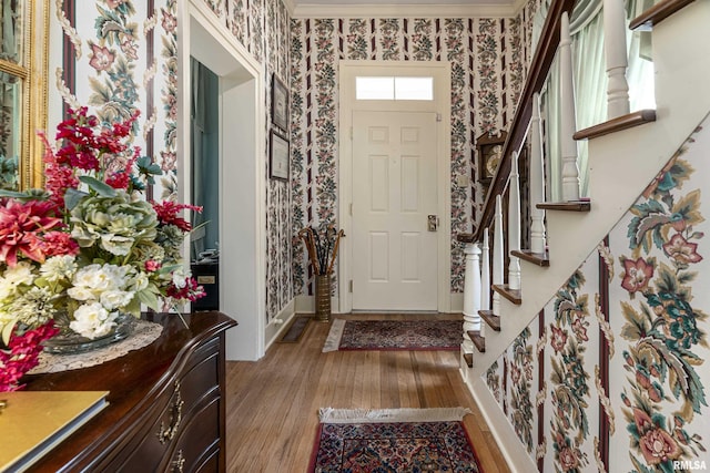 entryway featuring light wood-style flooring, crown molding, wallpapered walls, and stairway