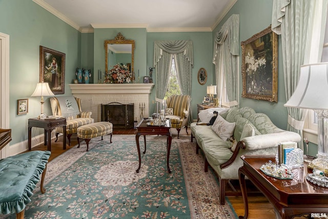 living area featuring wood finished floors, baseboards, ornamental molding, and a brick fireplace