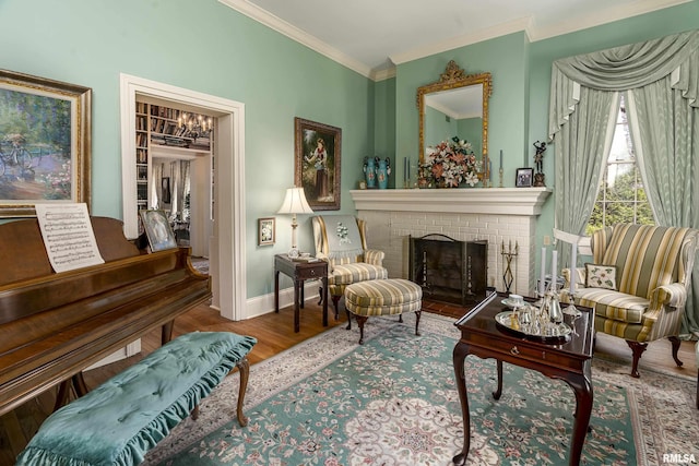 sitting room featuring crown molding, a chandelier, wood finished floors, a brick fireplace, and baseboards