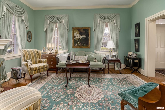 sitting room with ornamental molding, baseboards, wood finished floors, and a healthy amount of sunlight