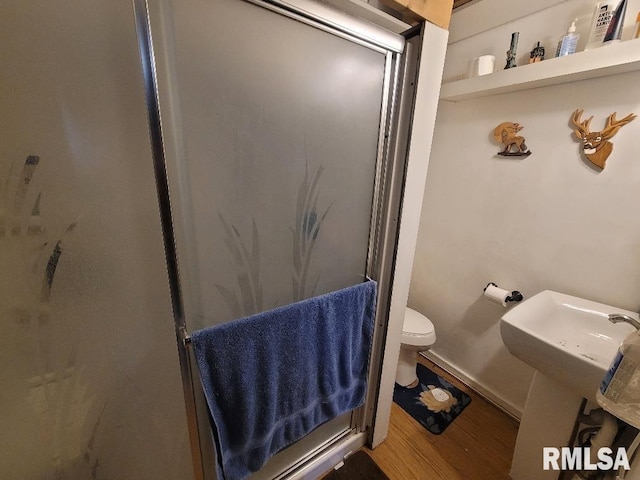full bath featuring toilet, a shower, wood finished floors, and baseboards
