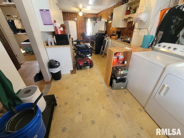 washroom with wood walls, laundry area, light floors, washer and dryer, and a sink